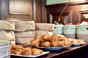 A breakfast buffet with croissants and other pastries on plates.