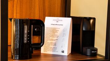 A coffee machine, a Krups coffee maker, and a user manual on a wooden surface.