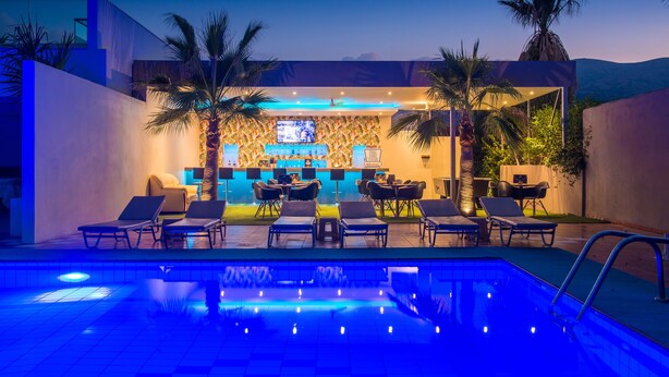 Een bar bij het zwembad met loungebedden, een bar en een televisiescherm.