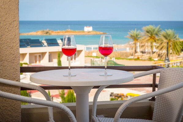 Two glasses of red wine on a balcony with a view of the sea and palm trees. - Primavera Beach Hotel (Hersonissos)