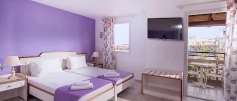 A bedroom with a bed, bedside tables, a TV, and a balcony with a table and chairs.