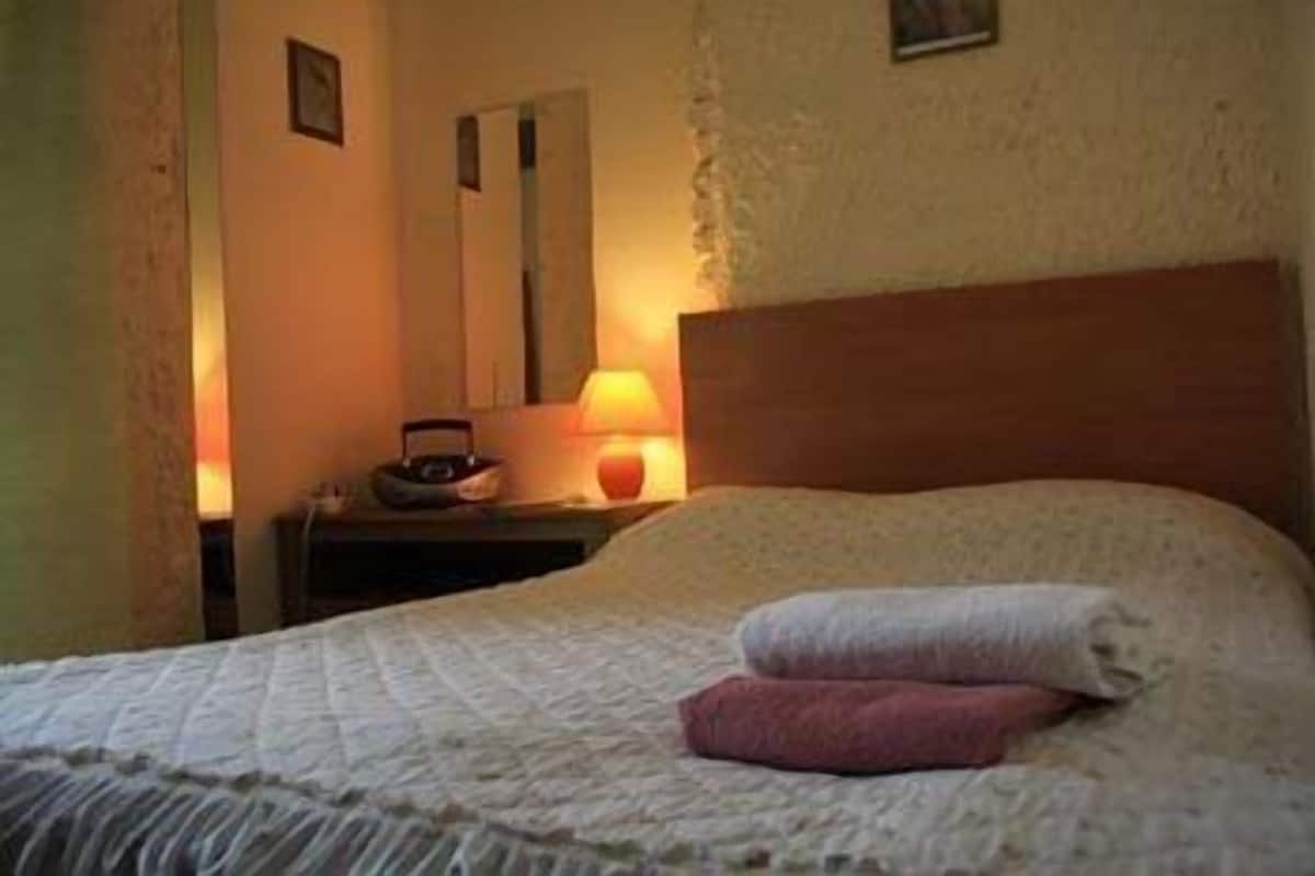 Una camera da letto con un letto, un comodino, una lampada e uno specchio.