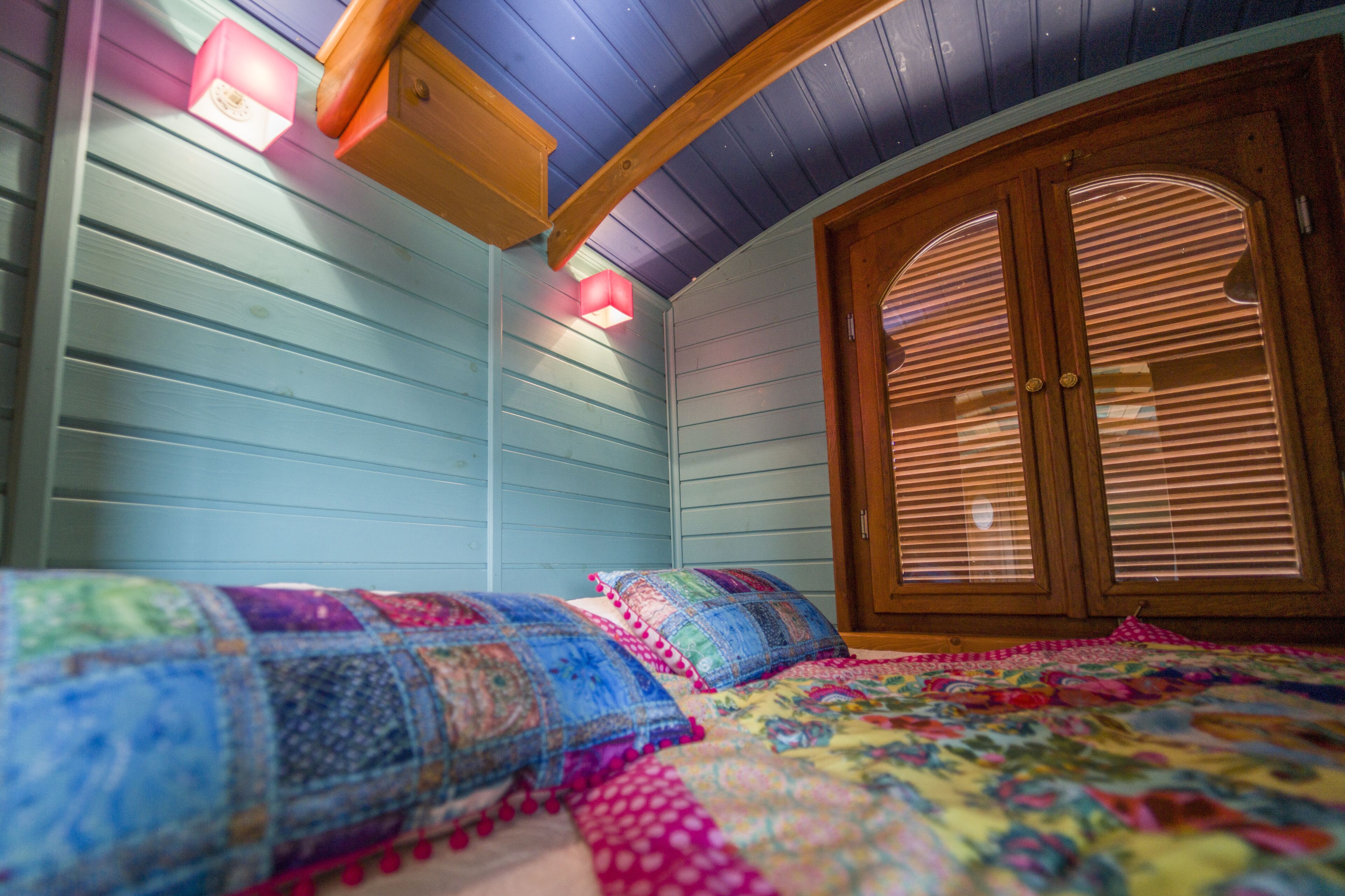 Ein Schlafzimmer mit zwei Betten, einer Holztür mit Fenster und einer Decke mit Holzbalken.