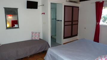 Quarto com duas camas de solteiro, uma televisão fixada na parede, um aparelho de ar condicionado e uma porta que dá para outro cômodo.