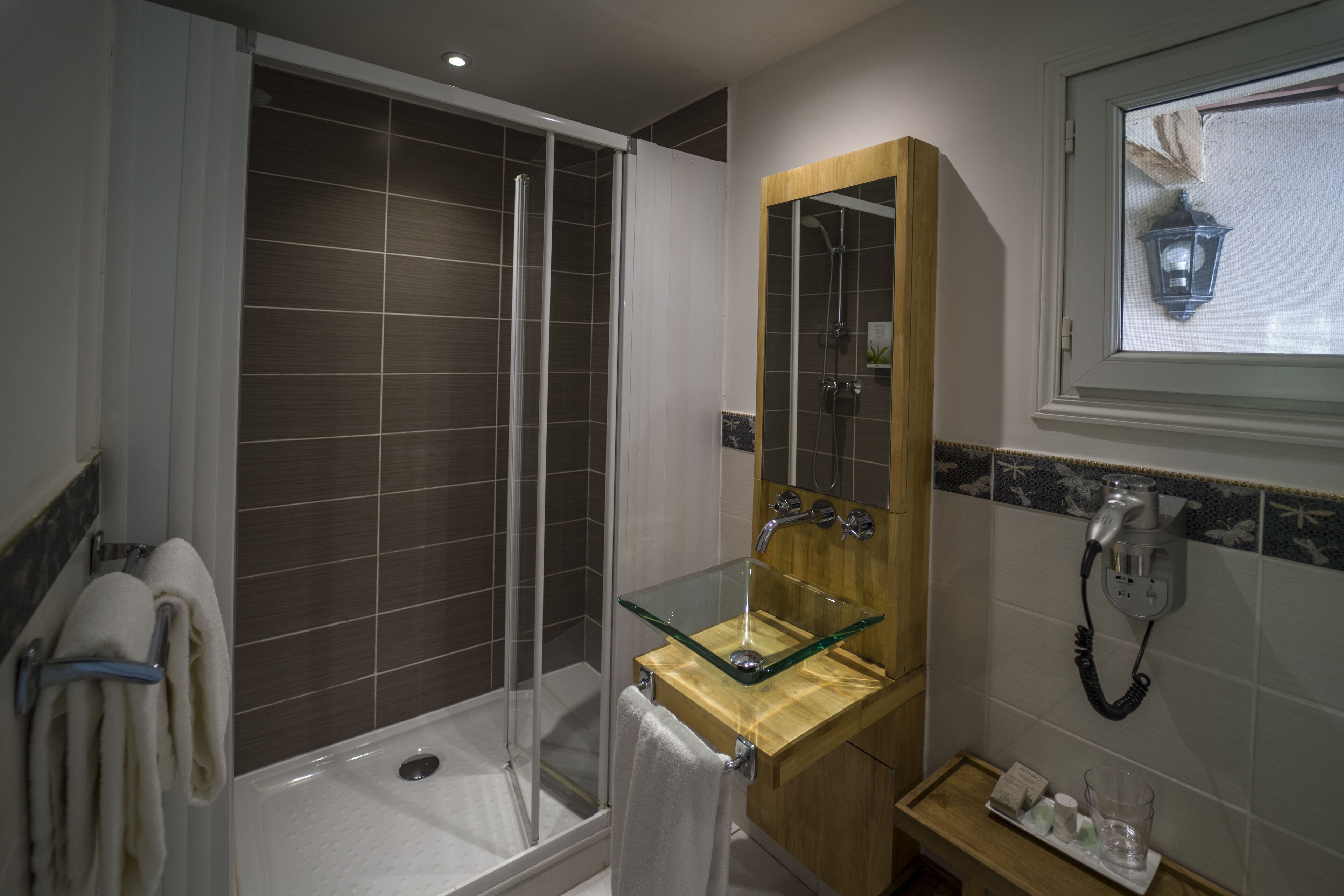 A modern bathroom with a glass shower enclosure, a wooden vanity with a glass sink, and a mirror above the sink.