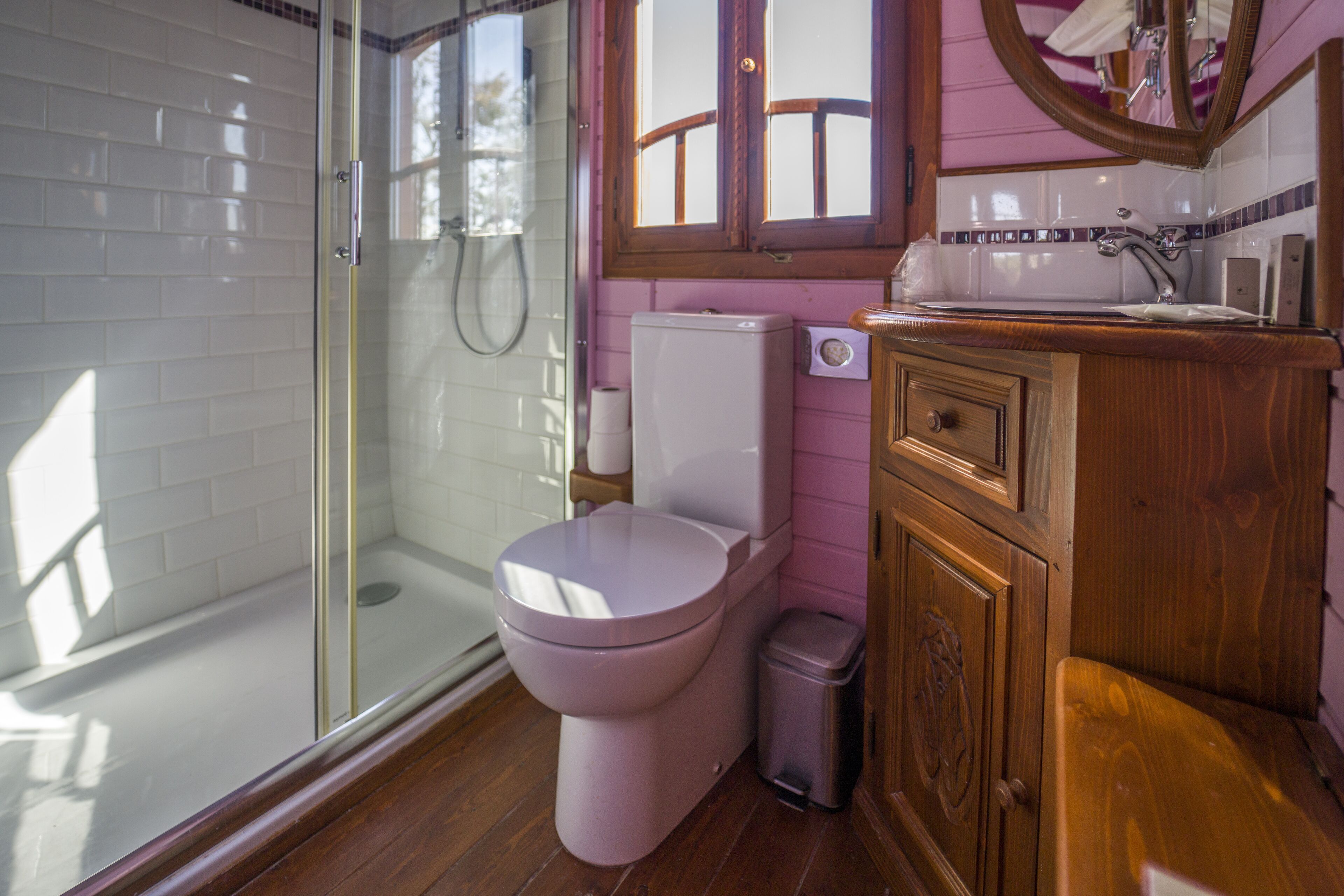 A bathroom with a glass-enclosed shower, a toilet, and wooden cabinetry.