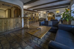 Un área de bar rústica con muebles de madera, una recepción y un suelo de piedra.
