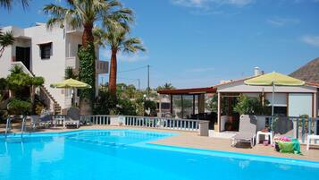 Alberca al aire libre, sombrillas en la alberca y camastros