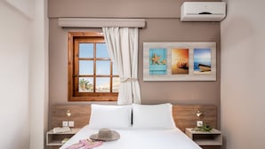 Een netjes ingerichte slaapkamer met een groot bed, een raam met gordijnen, een wandairconditioner en twee nachtkastjes met decoratieve objecten.