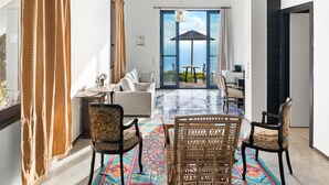 A modern living room with a sofa, two chairs, a dining table, and a colorful rug. - Serenity Boutique Hotel (Lefkada)
