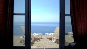 A room with a large window overlooking a beach with white lounge chairs. - Serenity Boutique Hotel (Lefkada)