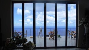 A room with a large sliding glass door leading to an outdoor terrace with a view of the sea. - Serenity Boutique Hotel (Lefkada)