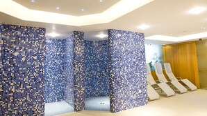 A modern spa area with mosaic tile walls, a seating area with lounge chairs, and a wooden panel wall. - Zenit Hotel Balaton (Vonyarcvashegy)