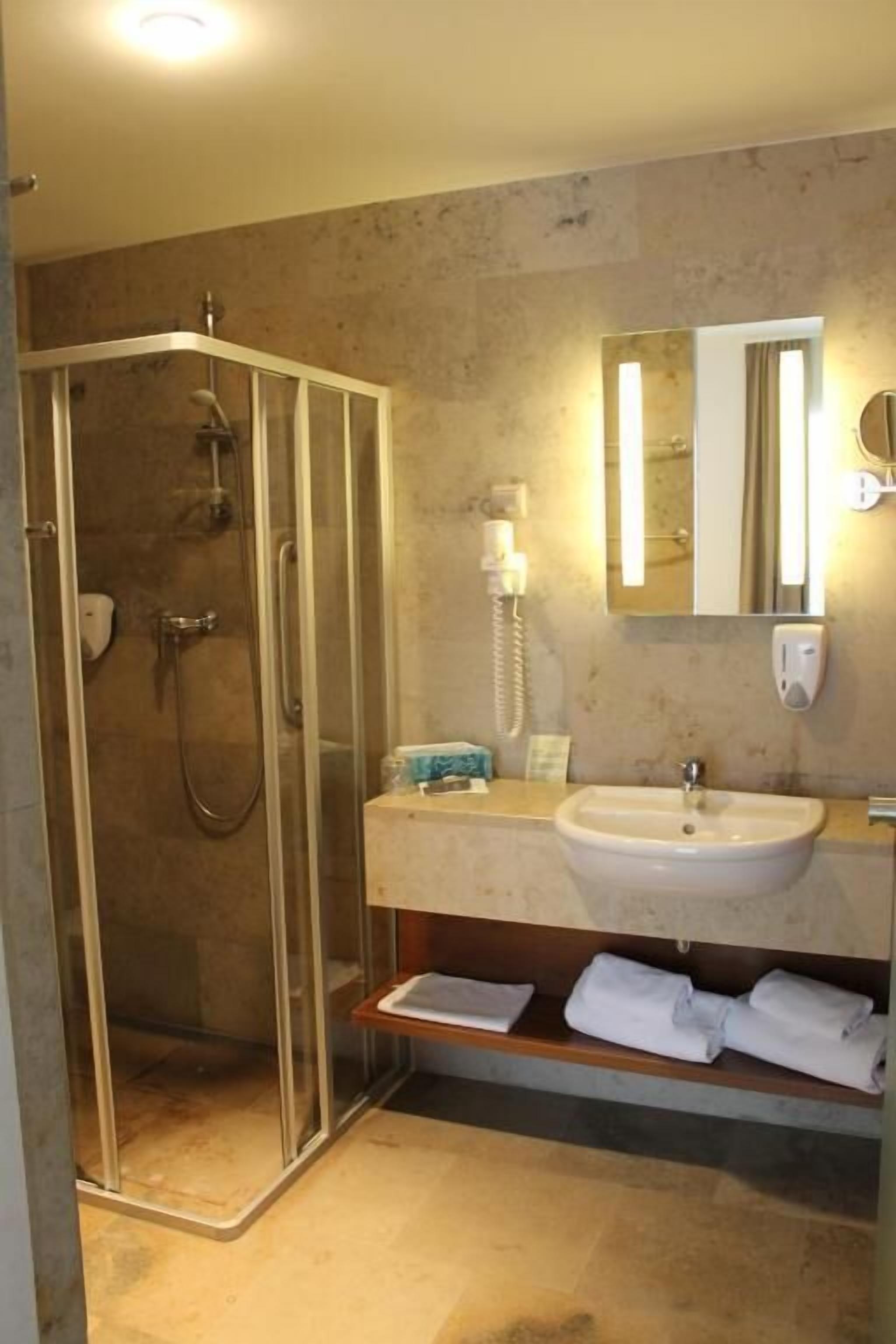 Un baño moderno con ducha envuelta en vidrio, lavamanos y espejo.