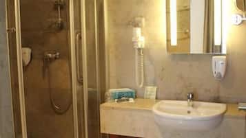 Un baño moderno con ducha envuelta en vidrio, lavamanos y espejo.