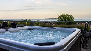 A hot tub with a view of the sea and houses in the background. - Zenit Hotel Balaton (Vonyarcvashegy)