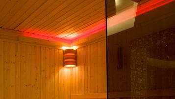A sauna with wooden walls and benches, a glass partition, and a tiled floor.