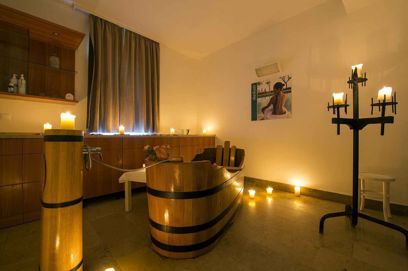 A spa area with a wooden tub, candles, and a wall-mounted candelabra.
