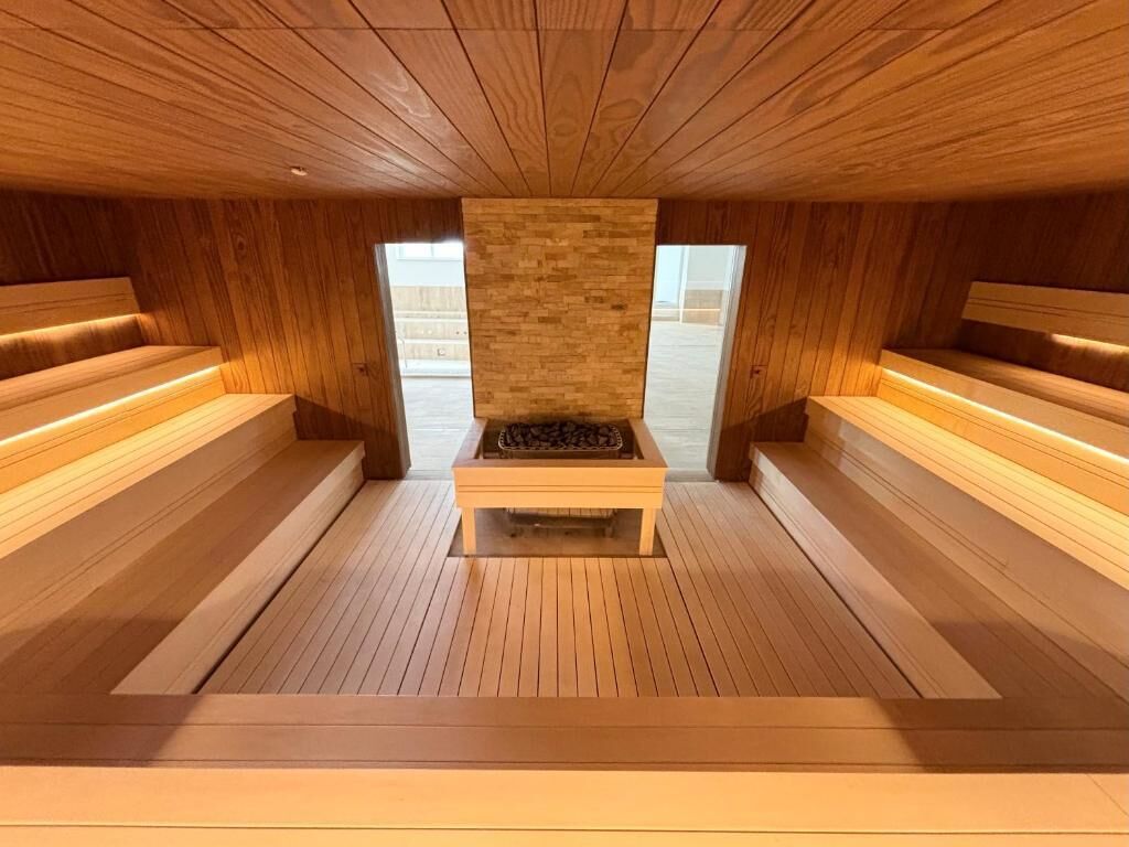 Una sauna con bancos de madera y una chimenea de piedra en el centro.