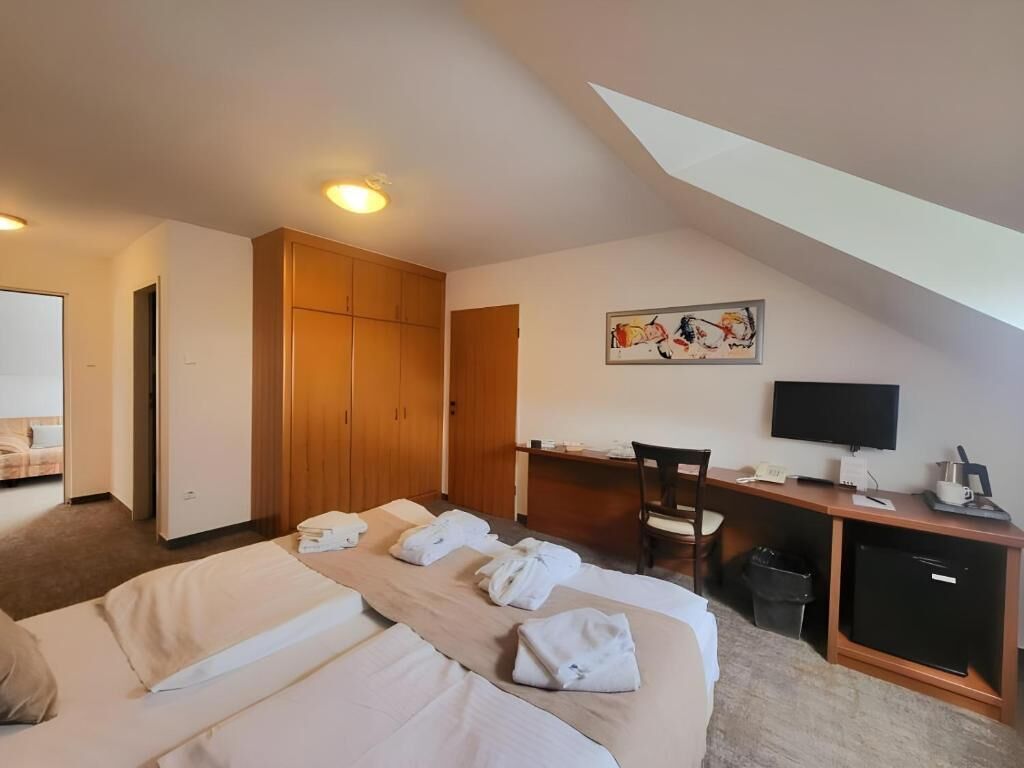 Hotellihuone, jossa on kaksi sänkyä, työpöytä, tuoli, televisio ja vaatekaappi.