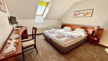Une chambre d’hôtel avec un lit, un bureau équipé d’un ordinateur, une chaise, une fenêtre et des œuvres d’art accrochées aux murs.