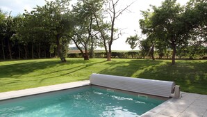 A swimming pool with a white deck, surrounded by a well-maintained lawn and trees. - Kamerijck Bed & Breakfast (Gingelom)