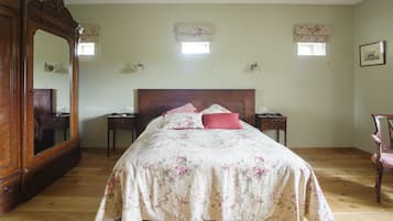 A bedroom with a large wooden bed, a dresser, two nightstands, and a chair.