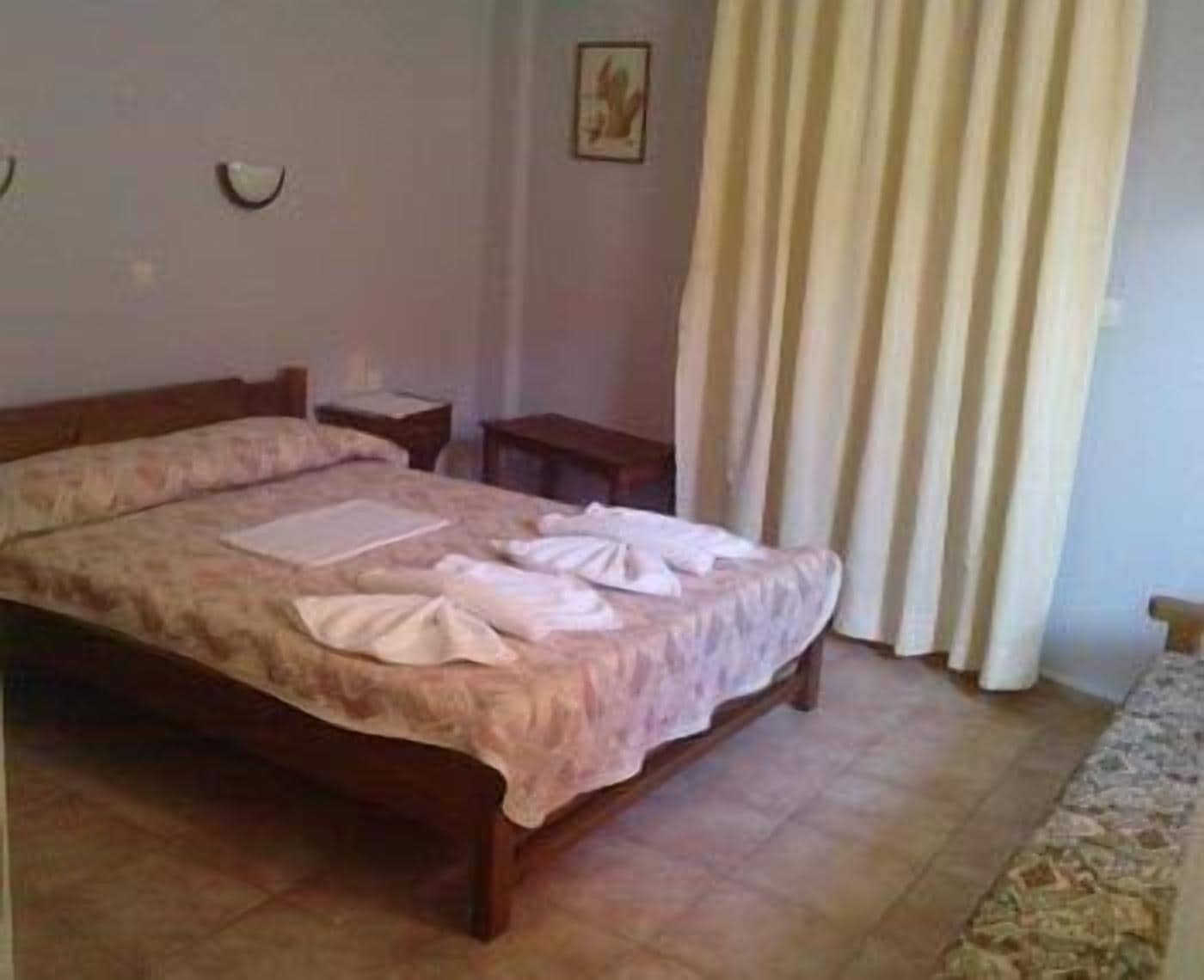 A neatly made bed with a floral bedspread, a bedside table, and a wall-mounted light fixture.