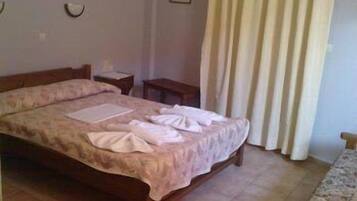 A neatly made bed with a floral bedspread, a bedside table, and a wall-mounted light fixture.