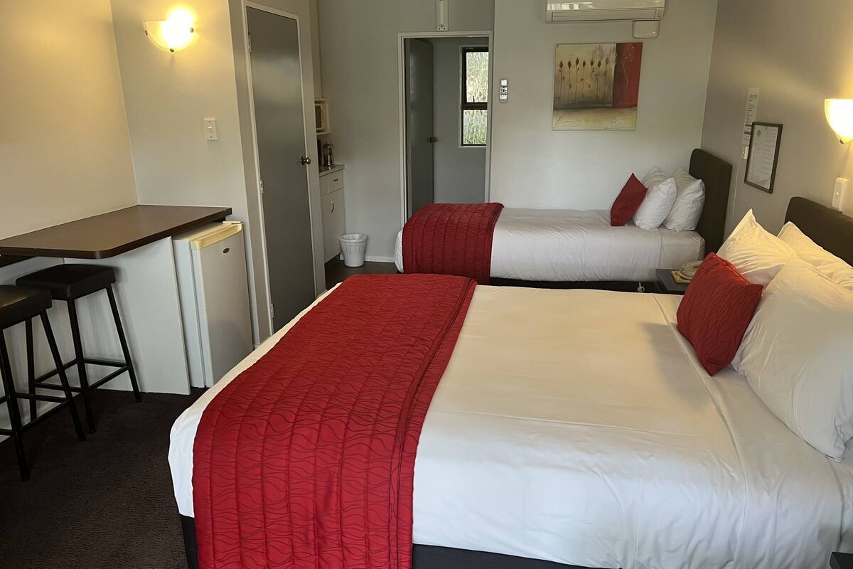 A hotel room with two beds, a desk, and a chair.