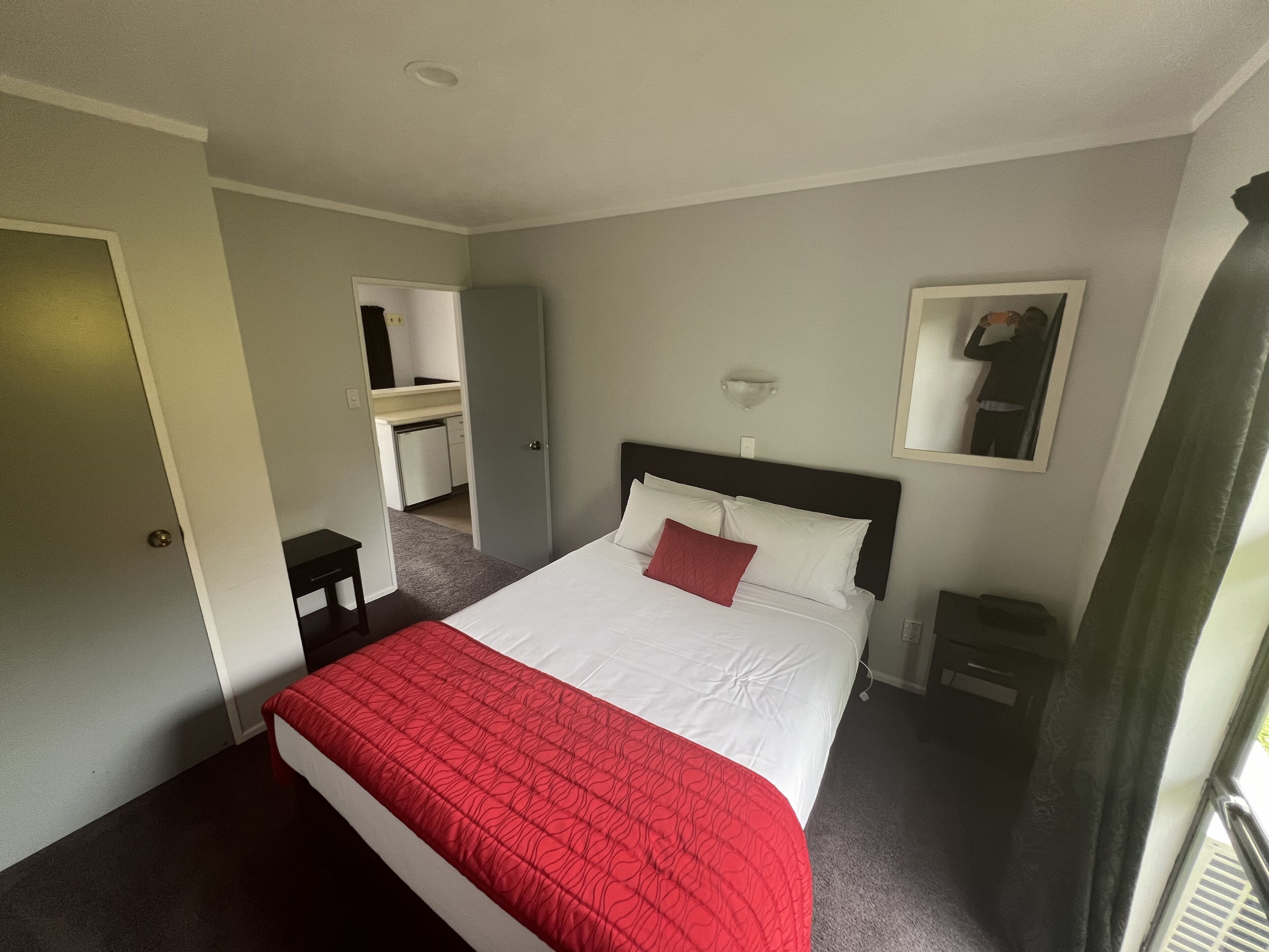 Una habitación de hotel con cama, escritorio, espejo y ventana.