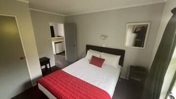 Una habitación de hotel con cama, escritorio, espejo y ventana.
