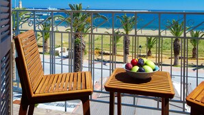 A balcony with two wooden chairs and a small table, a bowl of fruit, and a view of the sea. - Casa Maistra Residence (Rethymno)