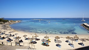 Une plage avec une eau d’un bleu limpide, des chaises longues et des parasols.