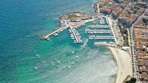 Vue aérienne d’une marina côtière, avec des bateaux amarrés, une jetée et des immeubles résidentiels adjacents.