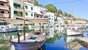 Un port de plaisance où sont amarrés des bateaux, entouré de bâtiments blancs aux volets et balcons verts.