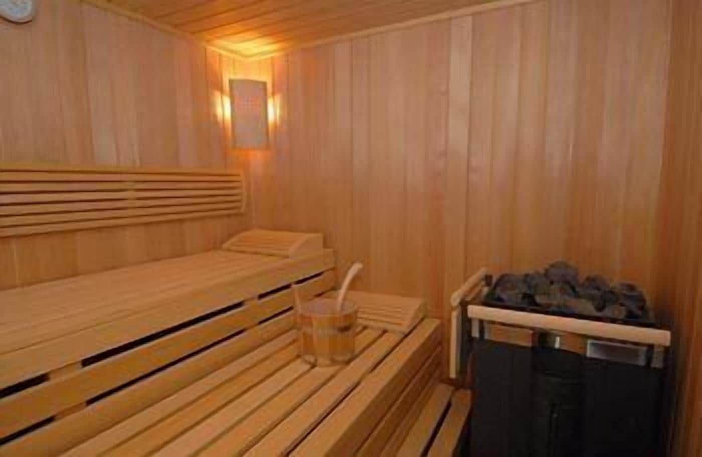 Un sauna con bancos de madera y un banco con una toalla y un vaso de agua.