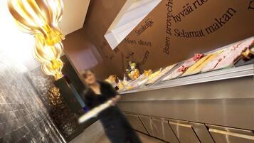 Una persona caminando cerca de una exhibición de comida con distintos productos y una pared con texto en un idioma extranjero.