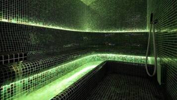 Un spa con suelo y paredes de azulejos, un banco curvo y una zona de ducha.