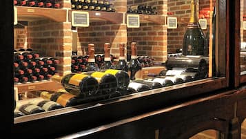 A wine cellar with wooden beams and brick walls, displaying various wine bottles and a wine rack.