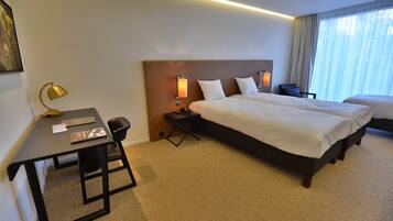 Une chambre d’hôtel avec un grand lit, un bureau avec une chaise, une lampe et une table de chevet.