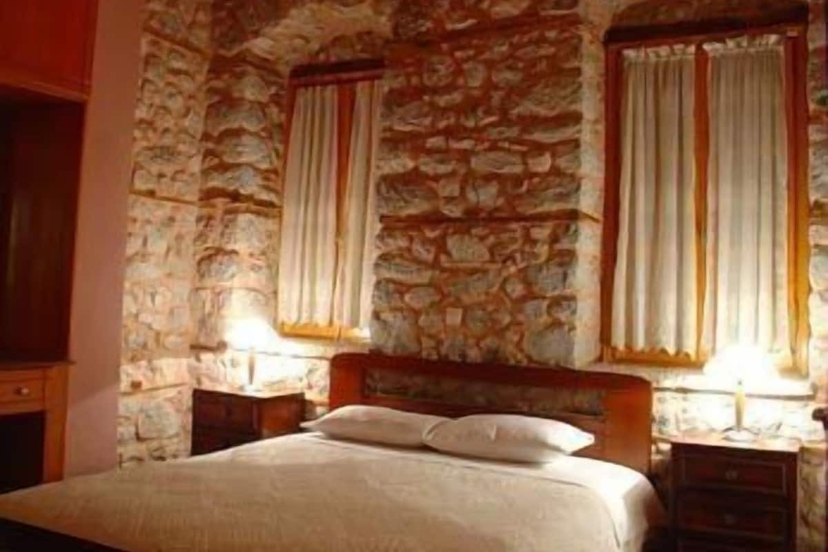Een slaapkamer met een wand met stenen patroon, een houten bedframe en twee nachtkastjes met lampen.