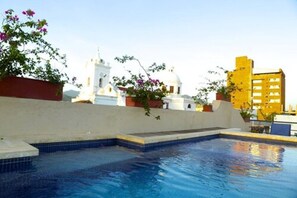 Una piscina al aire libre, sombrillas, sillones reclinables de piscina