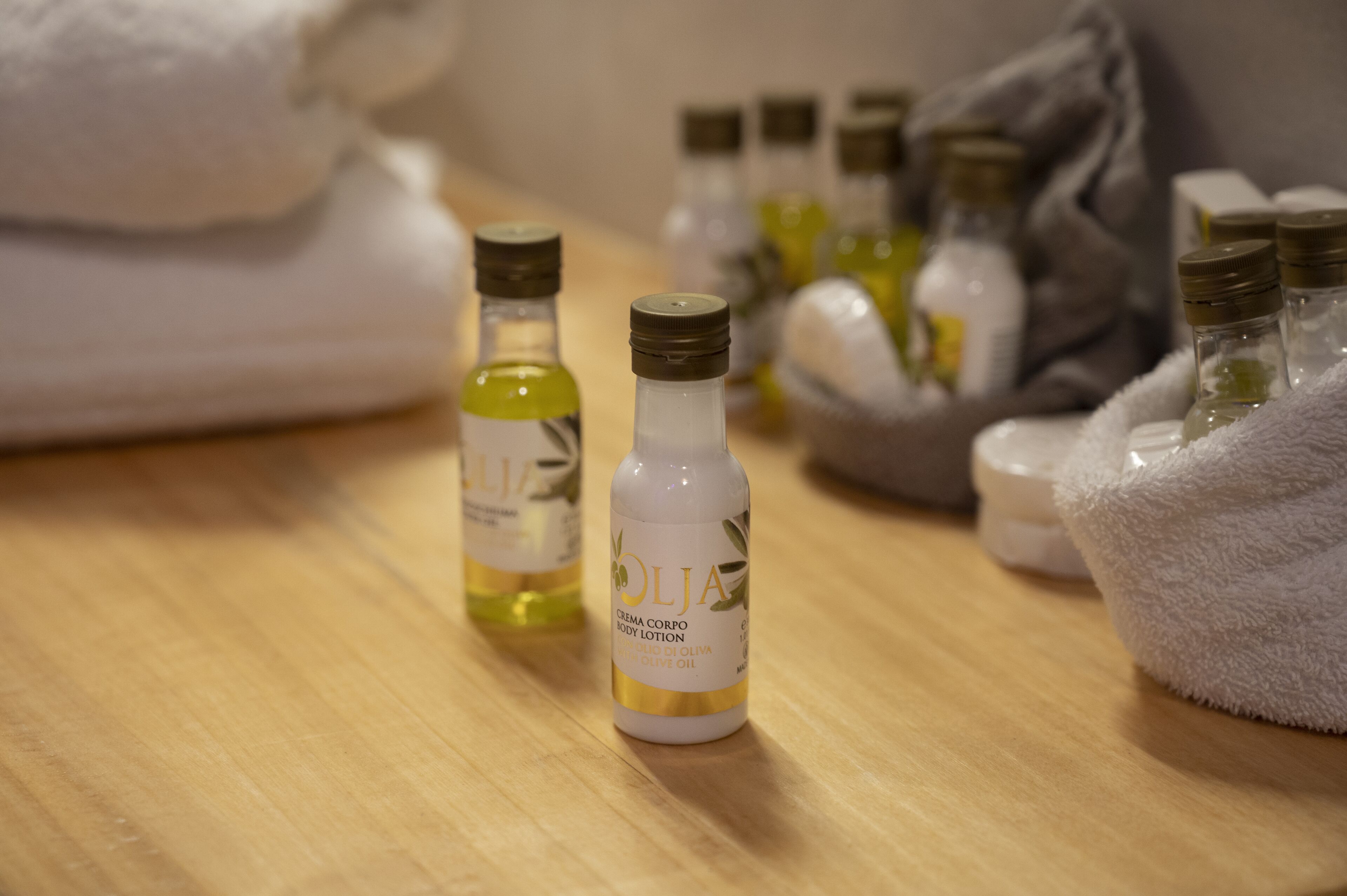A wooden surface with several bottles of body lotion and a white towel.