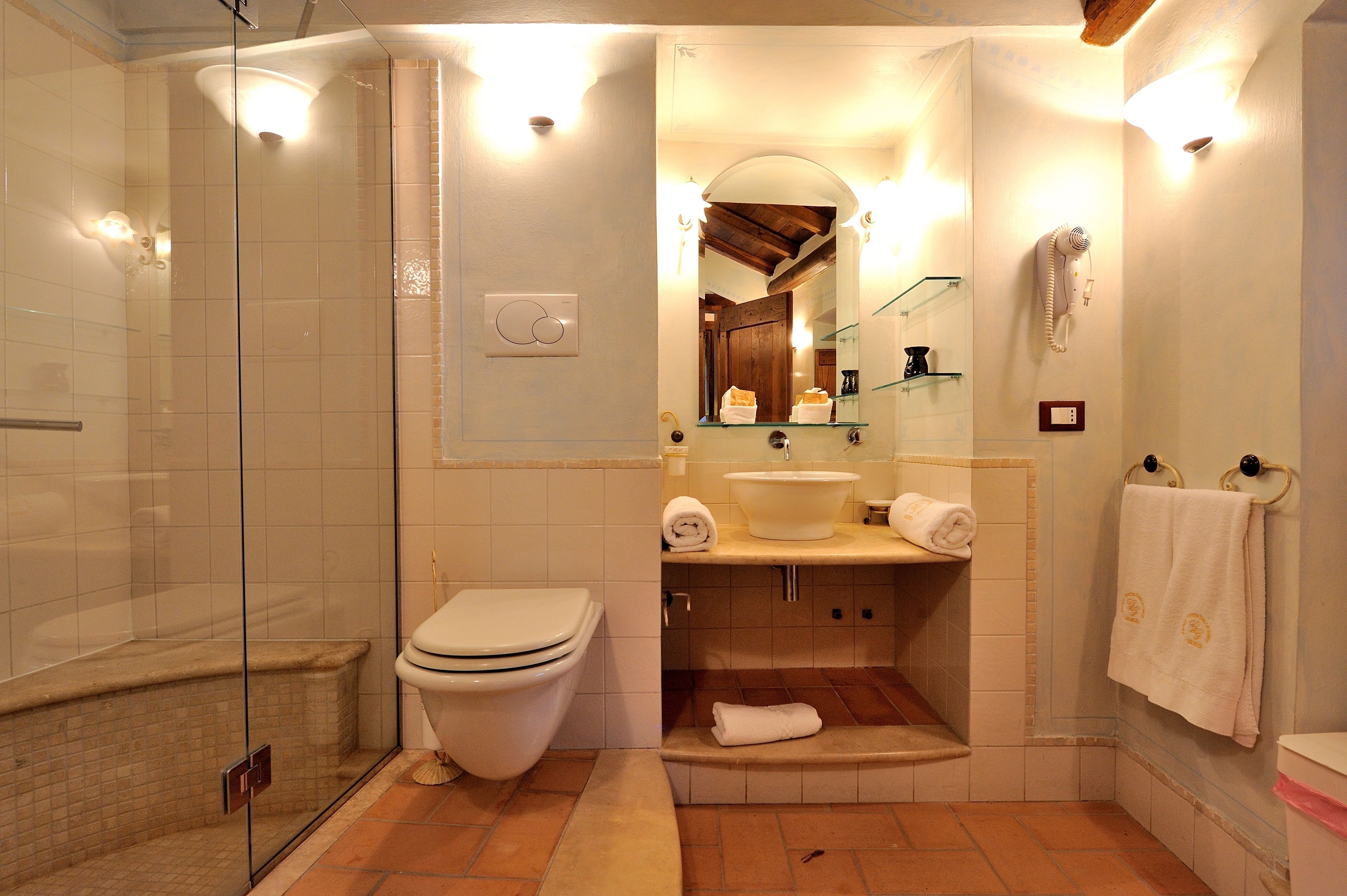 A bathroom with a glass-enclosed shower, a toilet, a sink, and a mirror.