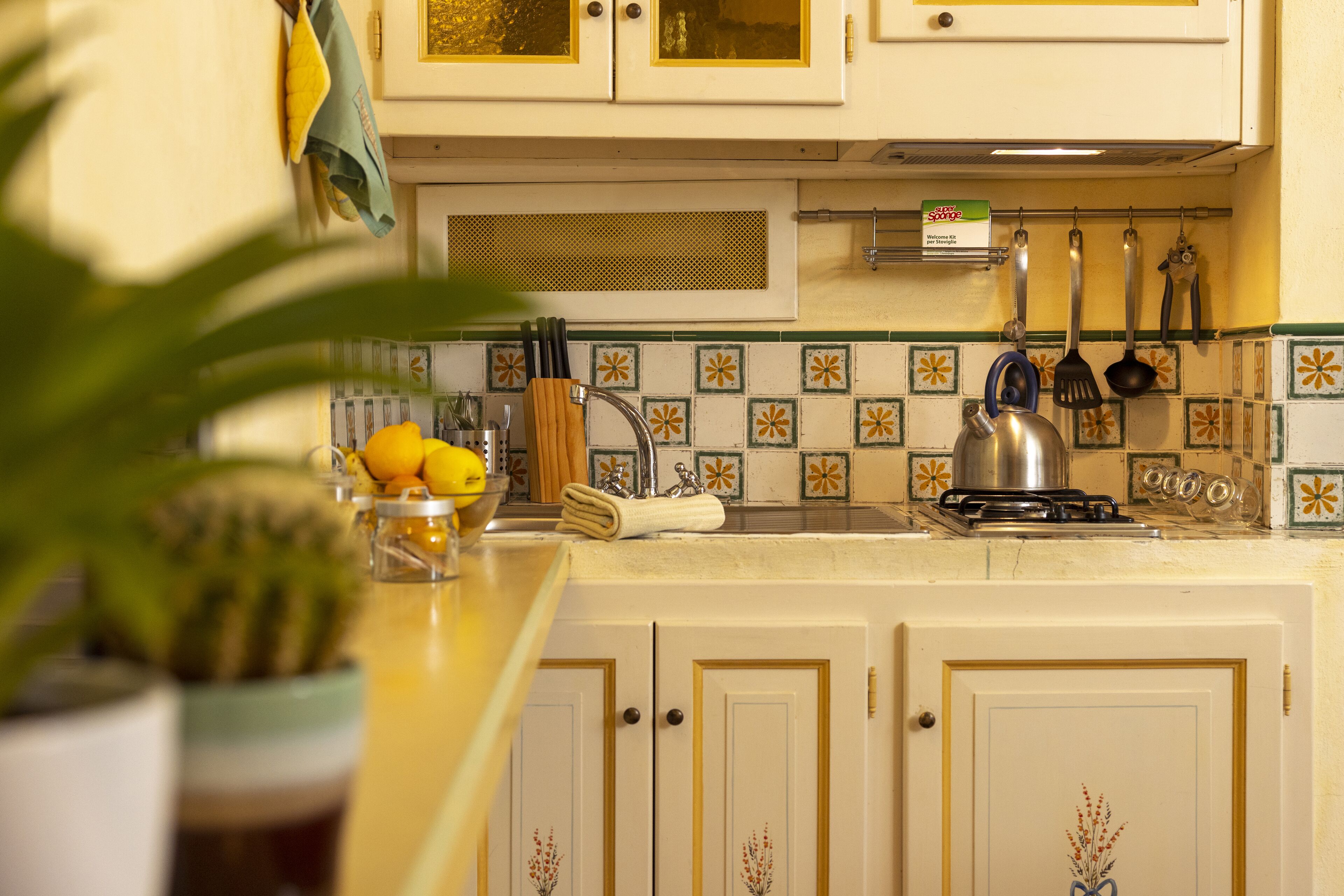 A kitchen with white cabinets, a stove, and hanging utensils.