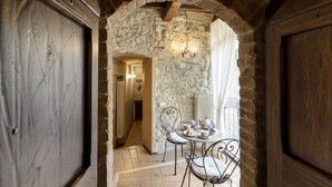 A rustic stone archway leading to a dining area with a table set for tea, a chair, and a wall-mounted light fixture. - Torre Del Nera Albergo Diffuso & Spa (Scheggino)