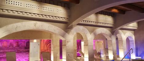 An indoor swimming pool with a modern design, featuring multiple arches and seating areas.