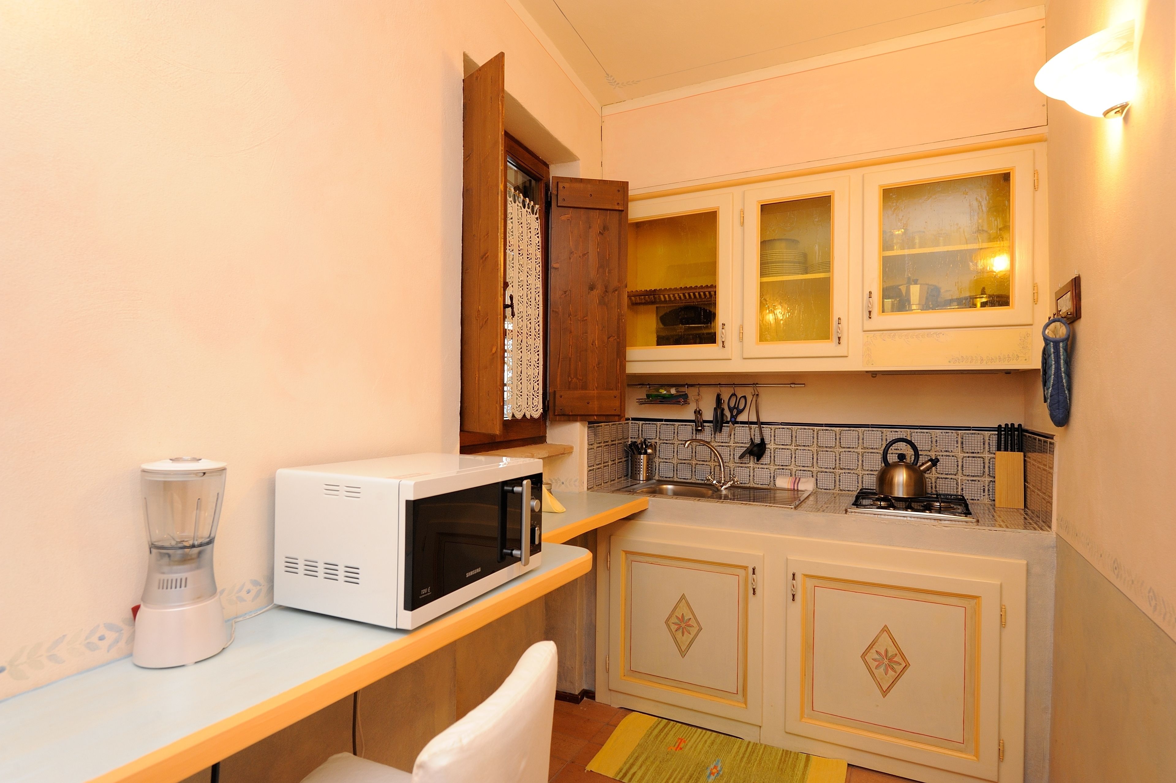 Une cuisine compacte équipée d’un four à micro-ondes, d’un mixeur et d’une petite cuisinière à gaz.