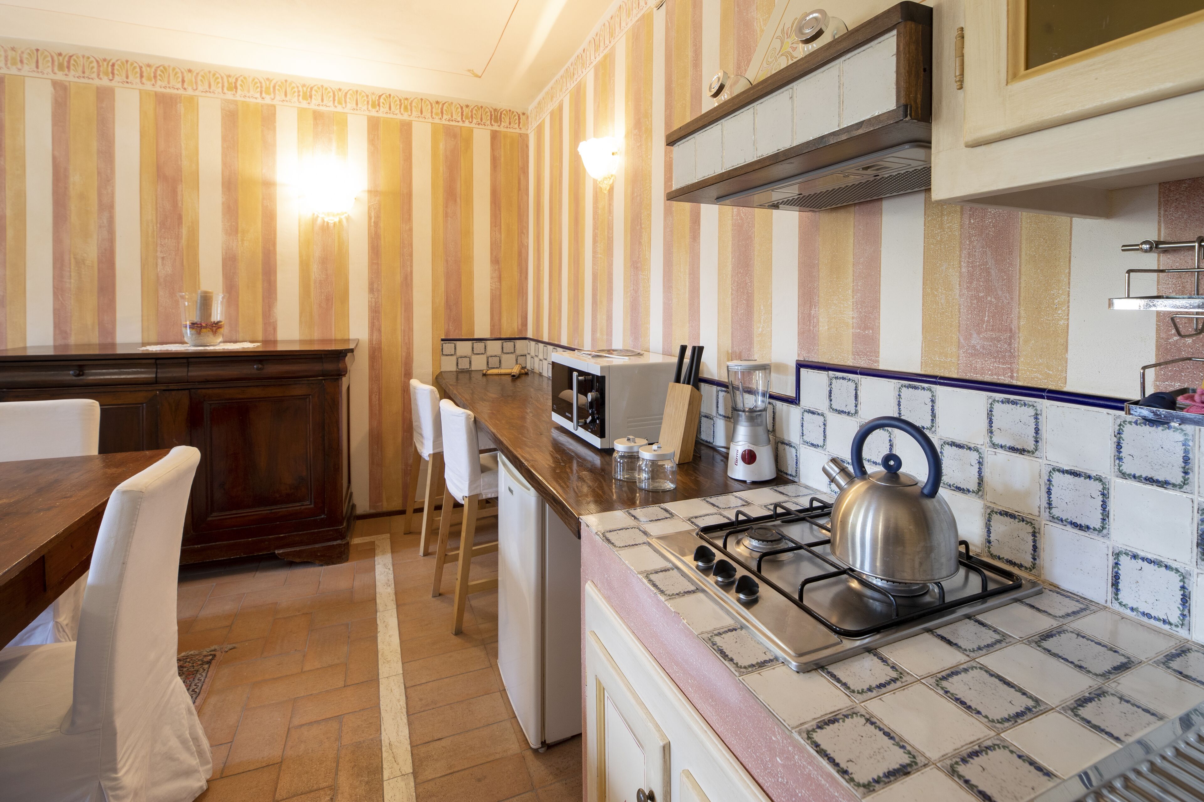 Una cocina con encimera de madera, estufa a gas, microondas y refrigerador.